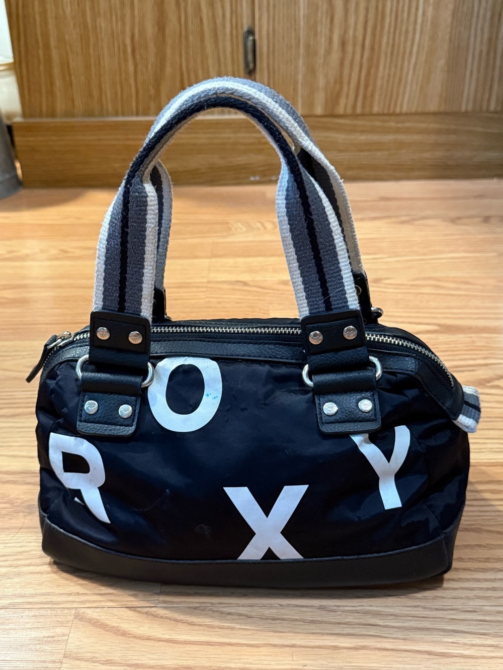 A vintage black nylon Roxy mini barrel shoulder bag featuring white lettering